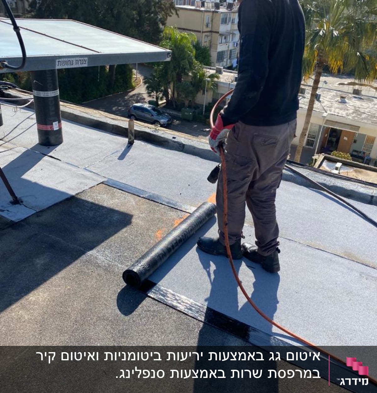 אדם עובד על גג עם יריעות ביטומניות